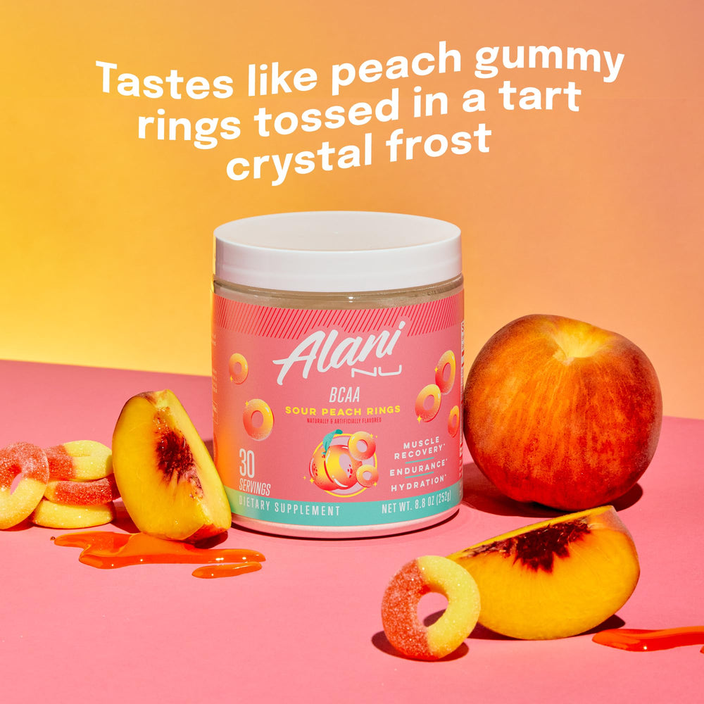 Alani Nu BCAA Sour Peach Ring scoop beside tub ready for mixing