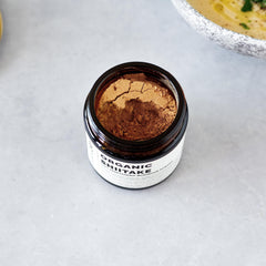 Erbology Shiitake powder in hot water mug releasing earthy aroma.