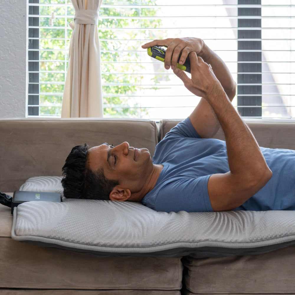 GhostBed massage mat shown on bed, couch, and floor for versatile use.
