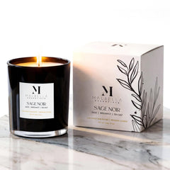 Sage Noire candle in a glossy glass vessel emitting ambient glow by Malbella Essentials.