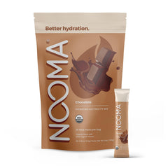 NOOMA chocolate electrolyte packet held over a glass for quick hydration.