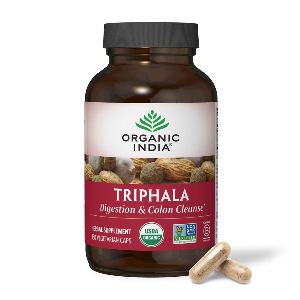 Triphala capsules on a desk scene suggesting a simple daily ritual.