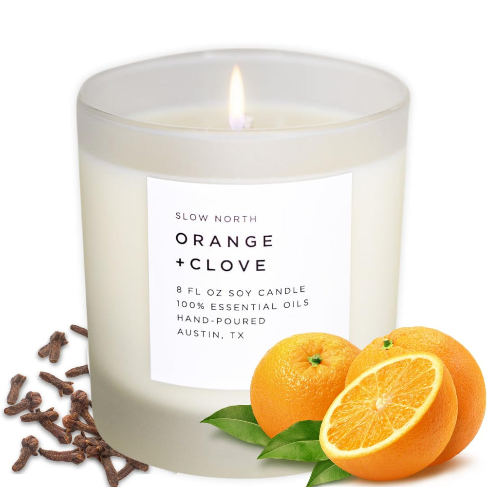 Slow North Orange and Clove Candle in a frosted jar enhances ambiance with citrus-spice aroma.