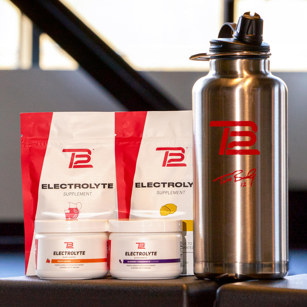 TB12 product box and stickpacks displayed on gym bench.