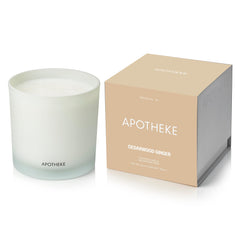 APOTHEKE Cedarwood Ginger 3-Wick Candle in a clear jar creates a warm living room ambiance.