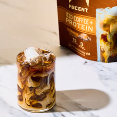 Ascent Caramel Iced Coffee Protein Powder tub with scoop for easy serving.