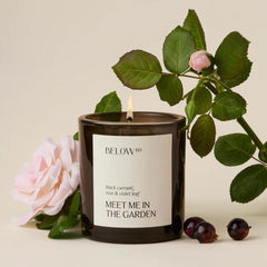 Below 60 Hilary Duff Meet Me in the Garden candle closeup for a cozy indoor ambiance.