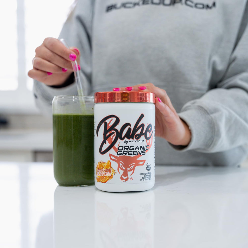 Scoop of Bucked Up Greens Orange Sunrise on a kitchen counter beside blender.