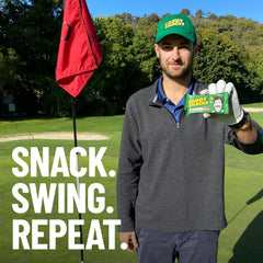 Caddy Snacks Chewy Cherry Almond bar resting beside golf tees for mid-round snack appeal