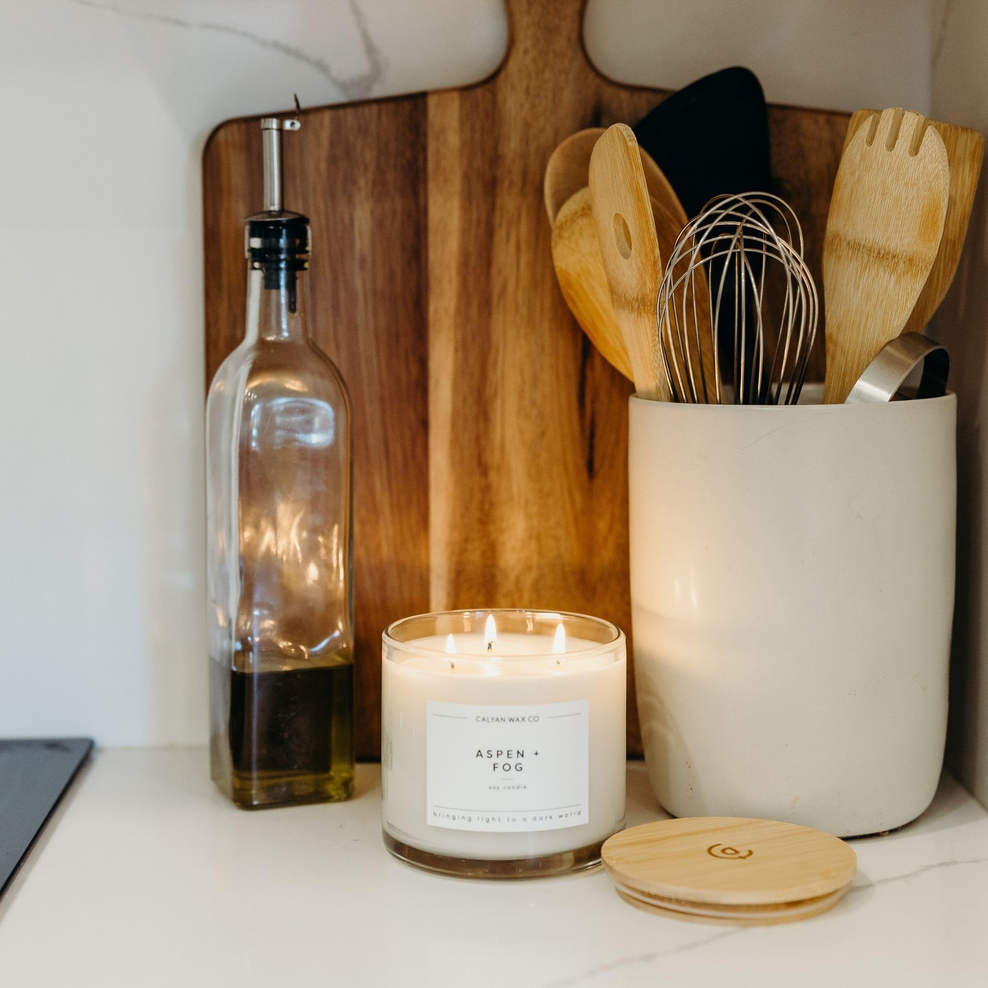 Aspen & Fog candle resting on a table in warm light.