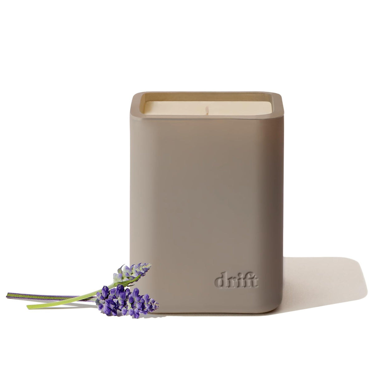 Drift Wild Lavender candle on wood surface with lavender sprigs enhances calm ambiance.