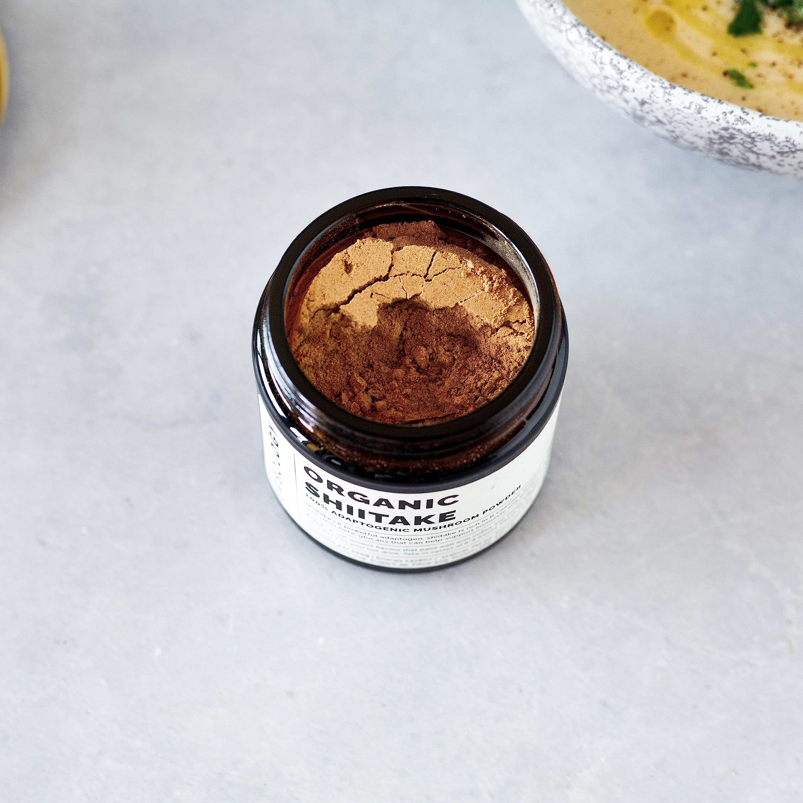 Erbology Shiitake powder in hot water mug releasing earthy aroma.