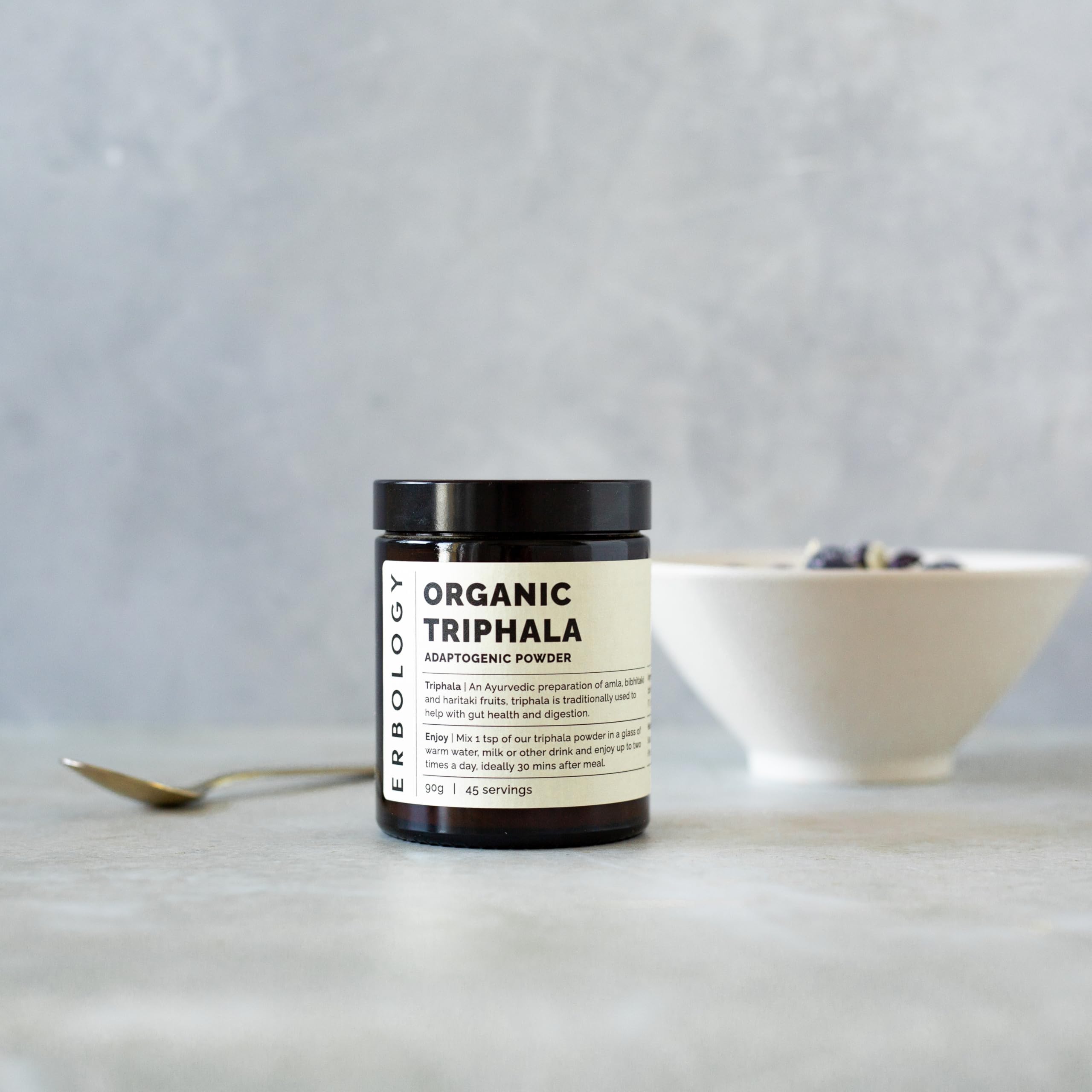 Erbology Triphala powder jar close-up emphasizes amber glass packaging preserving freshness.