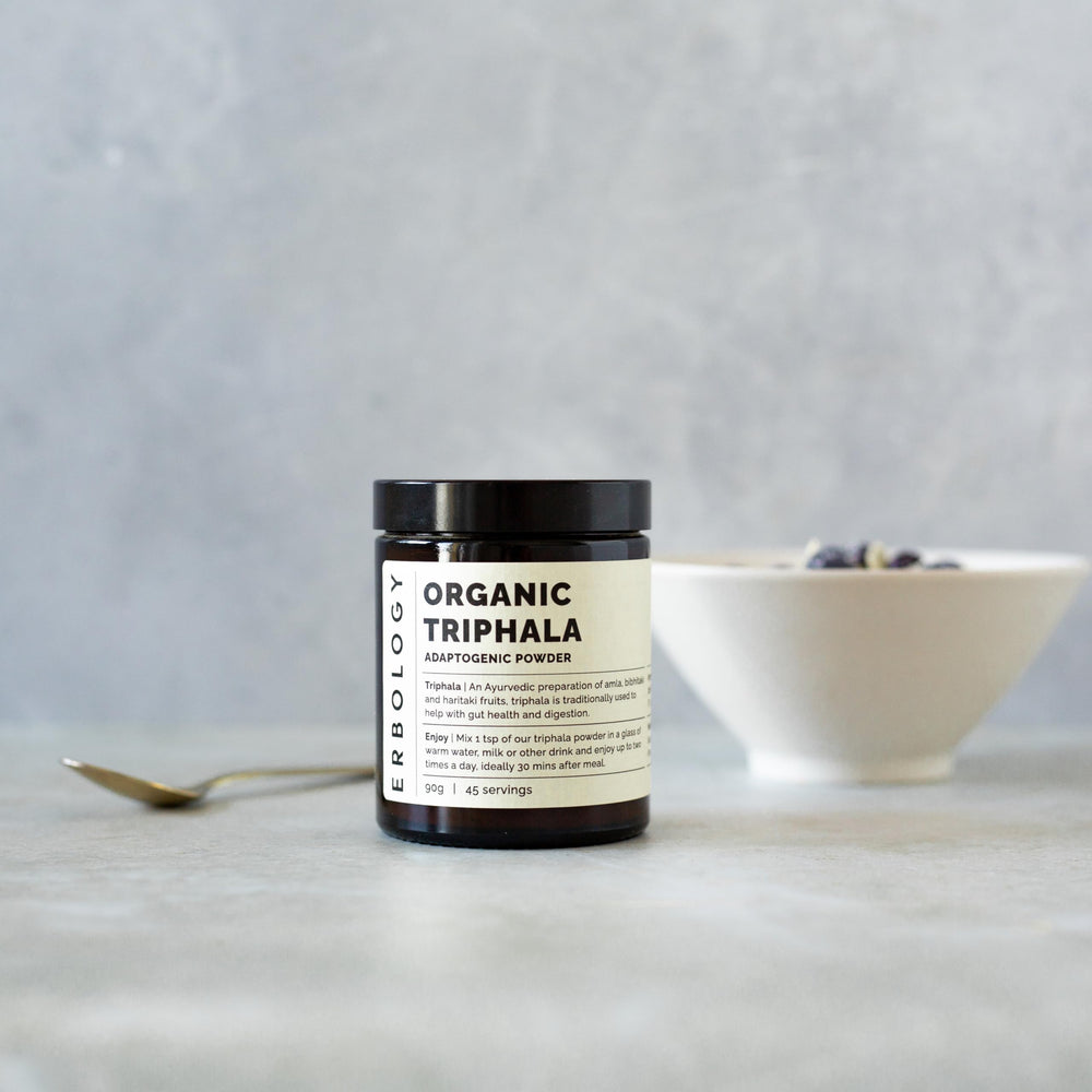 Erbology Triphala powder jar close-up emphasizes amber glass packaging preserving freshness.