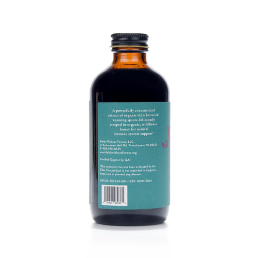 Fields Without Fences Elderberry Elixir on kitchen counter, fresh elderberries and spices suggest comforting daily use.