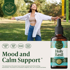 HERBAMAMA tulsi tincture dropper over a glass of water for easy daily use.