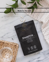 LongLiv Sleep Trio capsules arranged with water for bedtime routine.