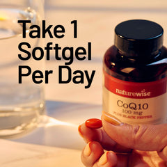 NatureWise CoQ10 softgels beside a glass of water for daily energy support.