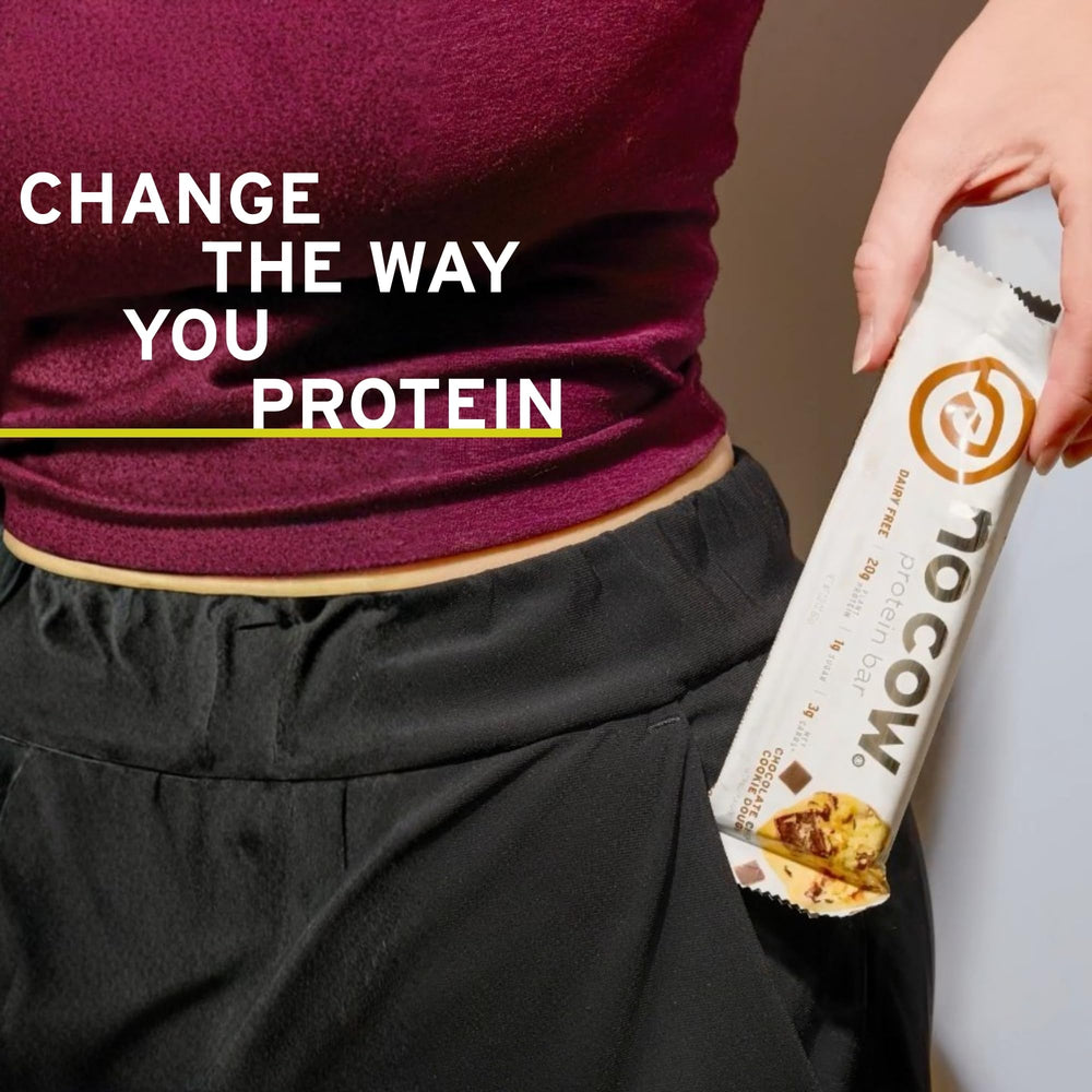 No Cow chocolate chip cookie dough bar beside gym gear, signaling active lifestyle use.