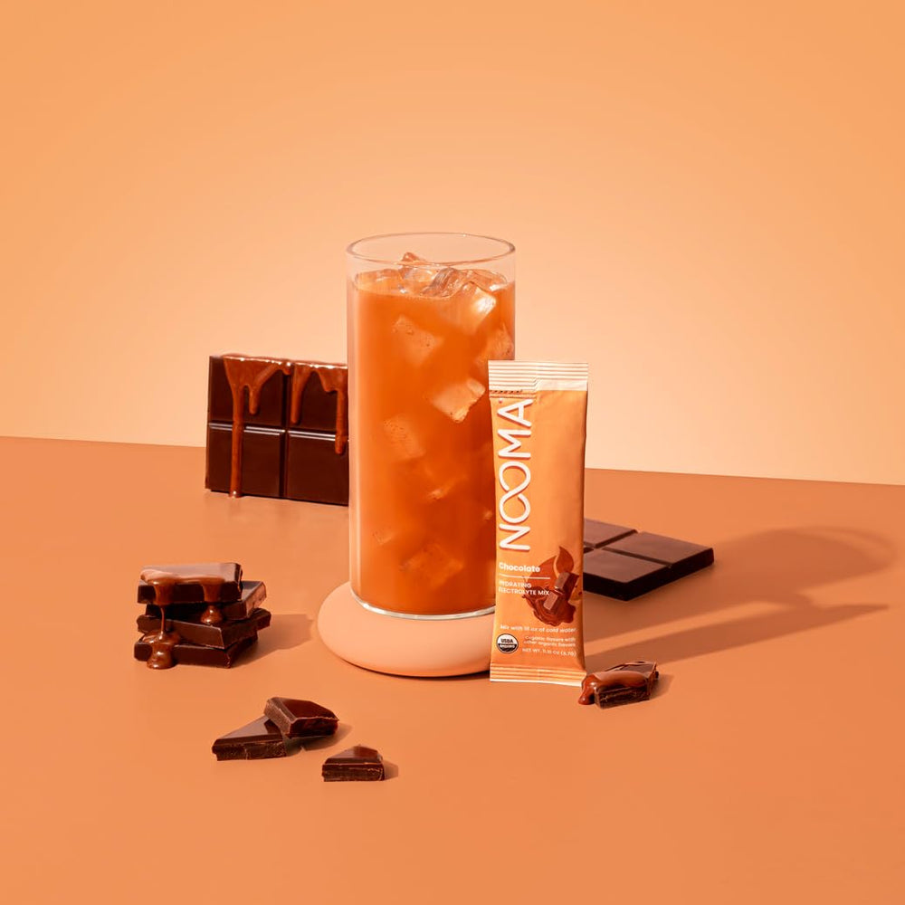 NOOMA chocolate electrolyte mix being poured into a glass for refreshment.