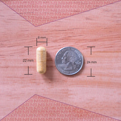 Close-up of a vitamin tablet shows non-GMO and allergen-free attributes.