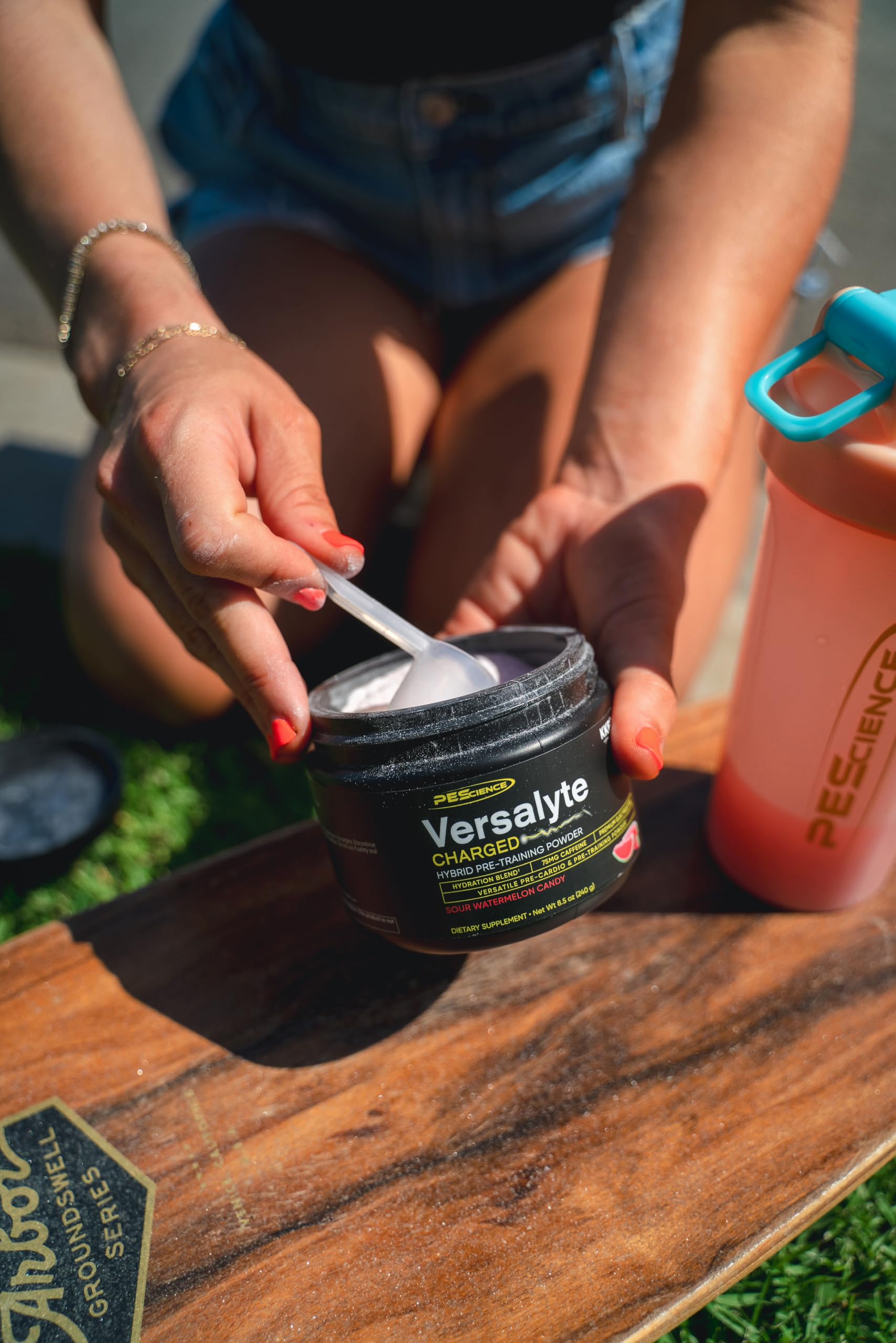 PEScience Versalyte Charged packets beside a bottle for on-the-go hydration.