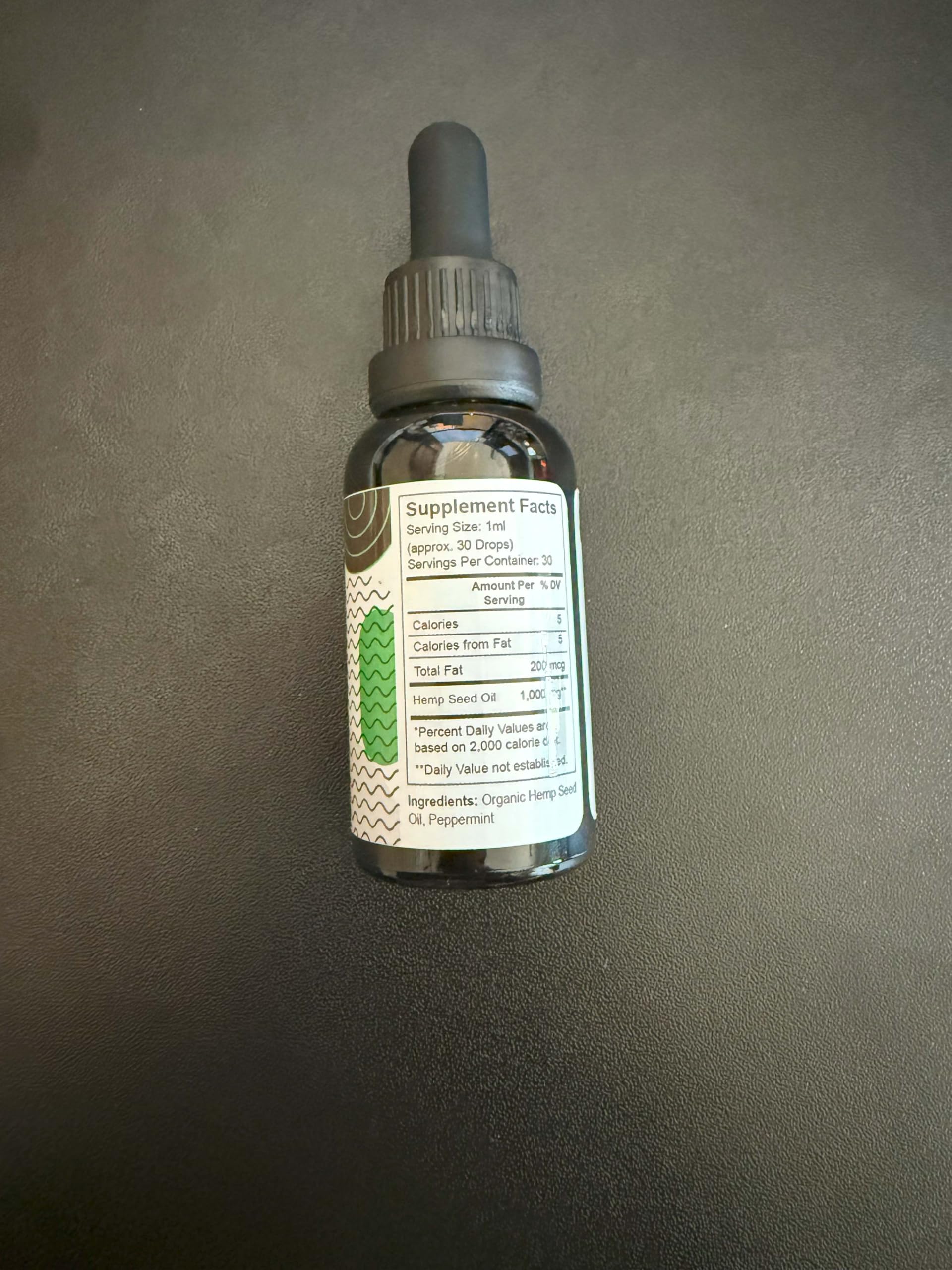 Glass bottle of Pure Wellness hemp seed oil against neutral background