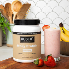 Rustic Nutrition premium whey powder scoop beside beverages for easy mixing.