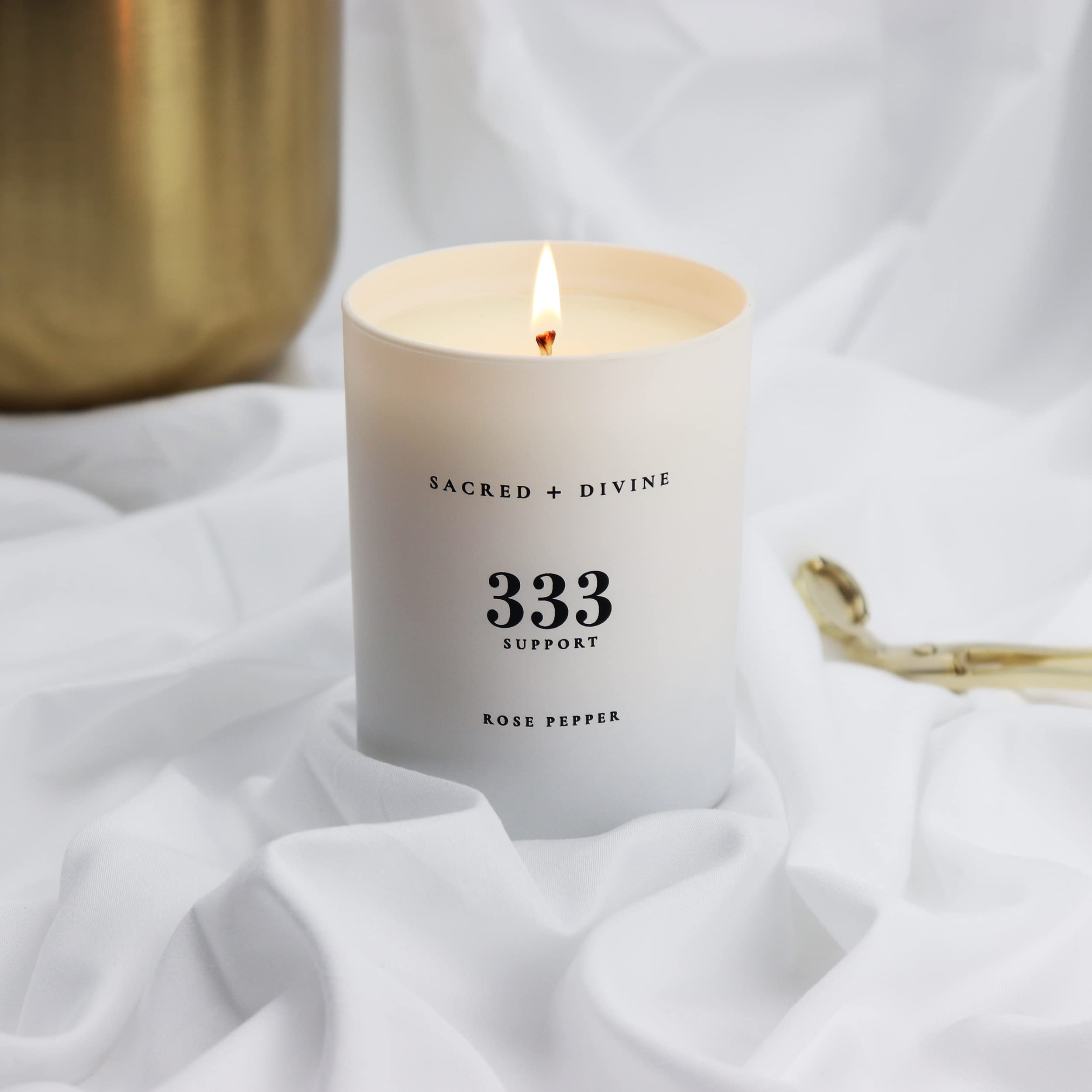 Lit Sacred + Divine 333 candle creating warm, reflective mood
