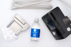 Snugell water beside the CPAP on a travel nightstand