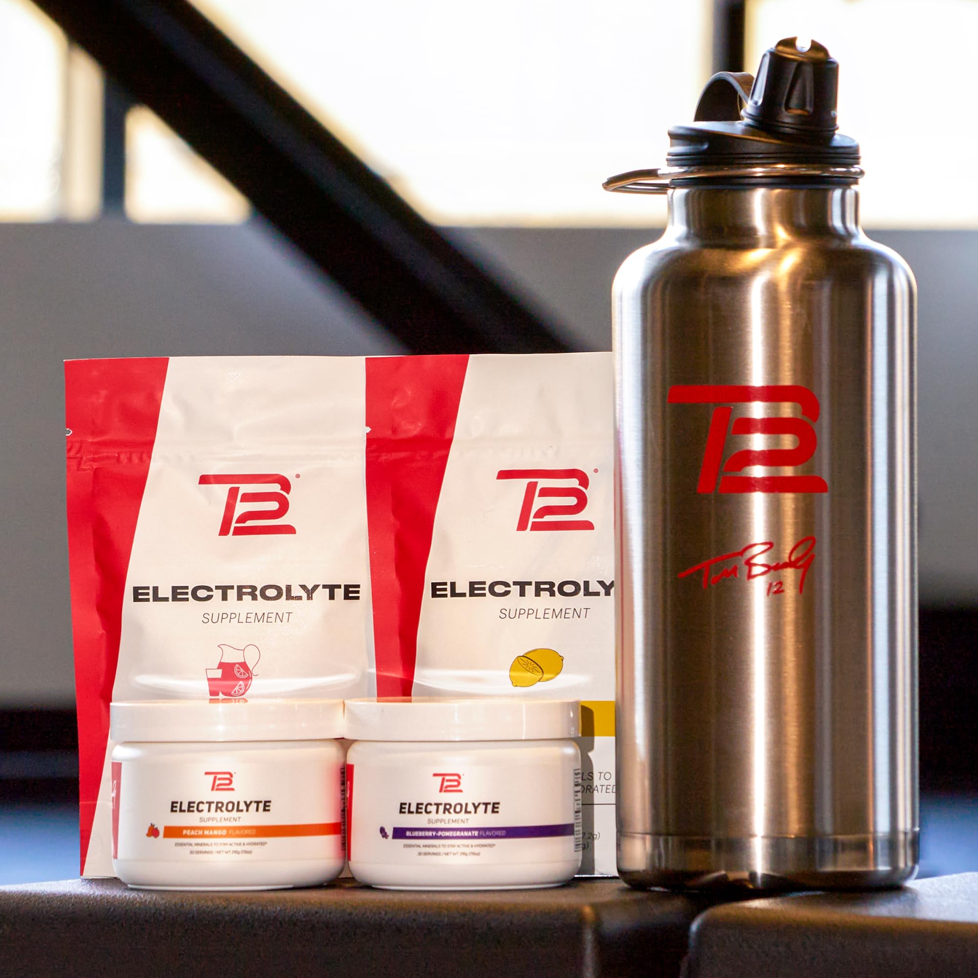 TB12 product box and stickpacks displayed on gym bench.