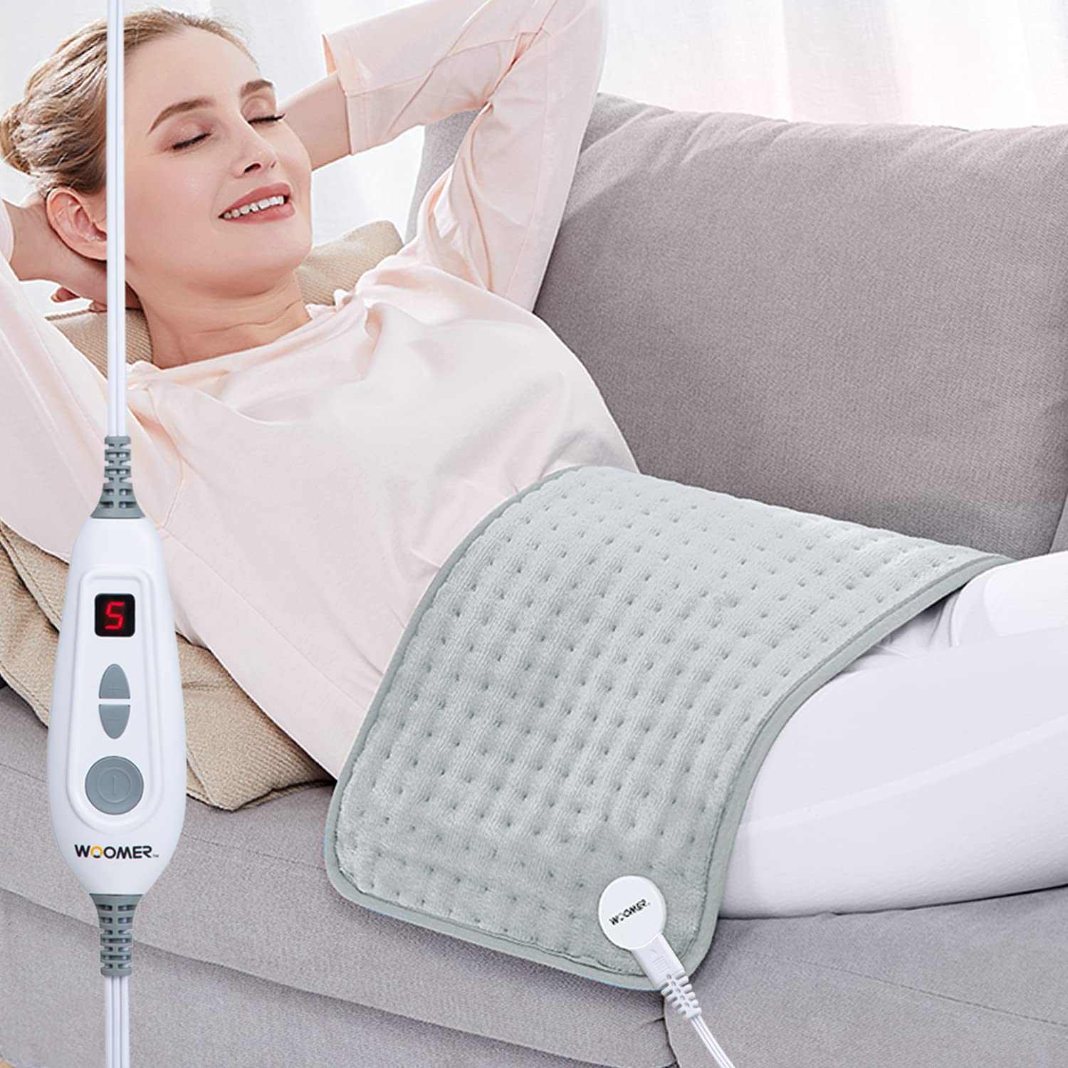 WOOMER extra-large heating pad on bed provides soothing warmth for full-body relief.